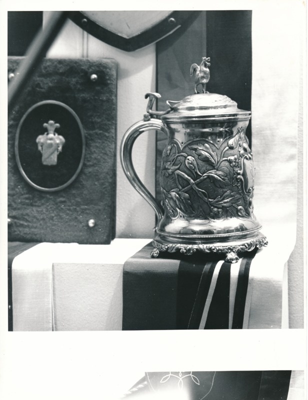 Üliõpilasorganisatsioonide näitus Tartu Linnamuuseumis 1989a. Hõbekann, peal taime ornamentika, kaane peal kuke kuju.