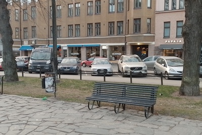 Karhupuisto. Agricolankatu. Mies nuokkumassa penkin päässä ja muita ihmisiä istumassa penkillä Karhupuiston laidalla puistotapahtuman aikaan. rephoto