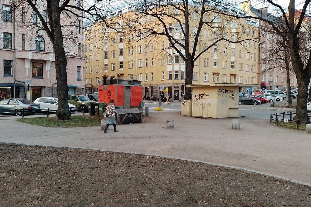 Karhupuisto. Muutama ihminen istuskelemassa lippakioskin nurkalla näyttämön katsomossa, joka oli rakennettu kaksiviikkoa kestävää puistotapahtumaa varten. rephoto