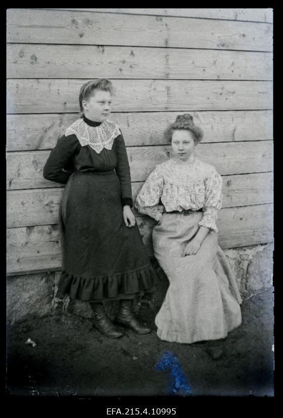 Kaks naist hoone välisseina taustal.