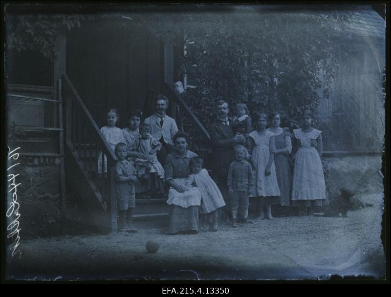 Viljandi Pauluse koguduse (maakoguduse) õpetaja Jaan Lattik (seisab, süles poeg Aldo Robert) sugulastega [ja külalistega] Viljandi kirikumõisa verandatrepil.