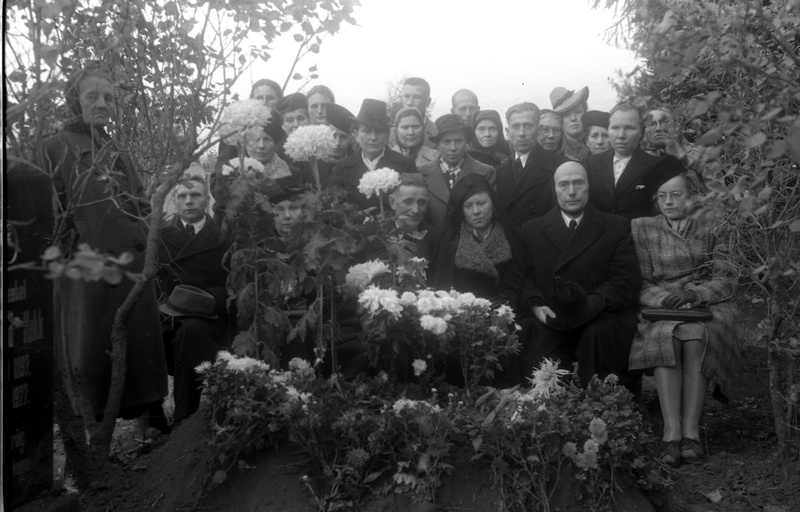 Inimesed seismas valgete krüsanteemidega kaunistatud värske hauakünka juures, kõrval veltveebel Ferdinand Kukk'e (1897-1927) hauasammas (matus)