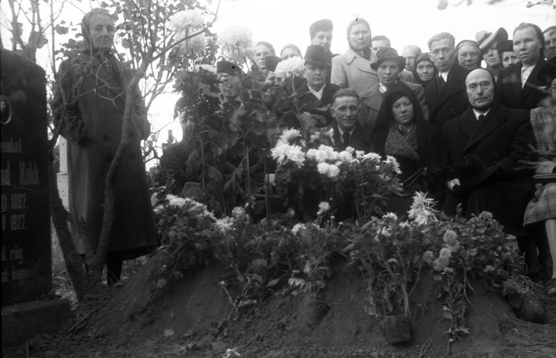 Inimesed seismas valgete krüsanteemidega kaunistatud värske hauakünka juures, kõrval veltveebel Ferdinand Kukk'e (1897-1927) hauasammas (matus)
