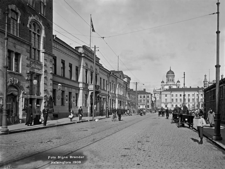Läntinen Rantakatu (Eteläranta) 16, 18, 20. Taustalla Nikolainkirkko (Helsingin tuomiokirkko) ja Seurahuone (kaupungintalo), Pohjoinen Esplanaadikatu (Pohjoisesplanadi) 11-13