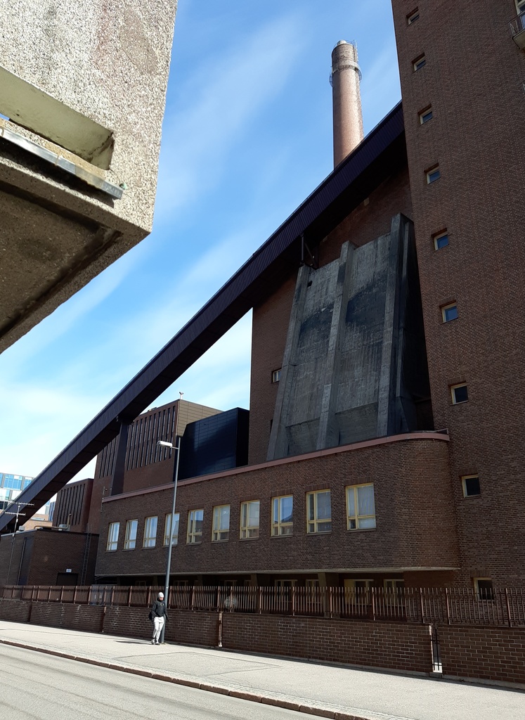 Osa Helsingin sähkölaitoksen Salmisaaren voimalaa, Lauttasaarenkatu 11 (nyk. Porkkalankatu 9-11), nähtynä Tallberginkadun varrelta, Porkkalankadun pohjoispuolelta. Voimalarakennuksen yläkertaan nousee hiiltä voimalan polttoaineeksi kuljettava linjasto. Voimala A otettiin käyttöön vuonna 1953. Valokuvan nurkissa näkyvät kaareutuvat tummat varjot, jotka johtuu siitä, että valokuvaaja on käyttänyt kuvatessaan vastavalosuojaa. rephoto
