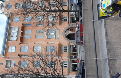 Fabianinkatu 13. Ihmisiä kävelemässä sateisella Fabianinkadulla jugendtalo Torilinnan sisäänkäynnin ja porttikäytävän edustalla Kasarmitorin laidalla. rephoto