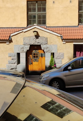 Kiinteistö Oy Eol, Luotsikatu 5 A. Arkkitehtitoimisto Gesellius, Lindgren, Saarinen. Sisäänkäynti. Jykevässä puuovessa koristeellisia takorautadetaljeja (helat, ikkunakehys) sekä värillisestä lasista valmistettu neliruutuinen ikkuna. Luonnonkiviportaali, jossa puskevat pässit. Vuonna 1901 suunniteltu talo on hyvä esimerkki alkuperäisessä asussaan säilyneestä Katajanokan art nouveau -kaupunginosan luonnonkivestä ja tiilestä rakennetusta asuintalosta. rephoto