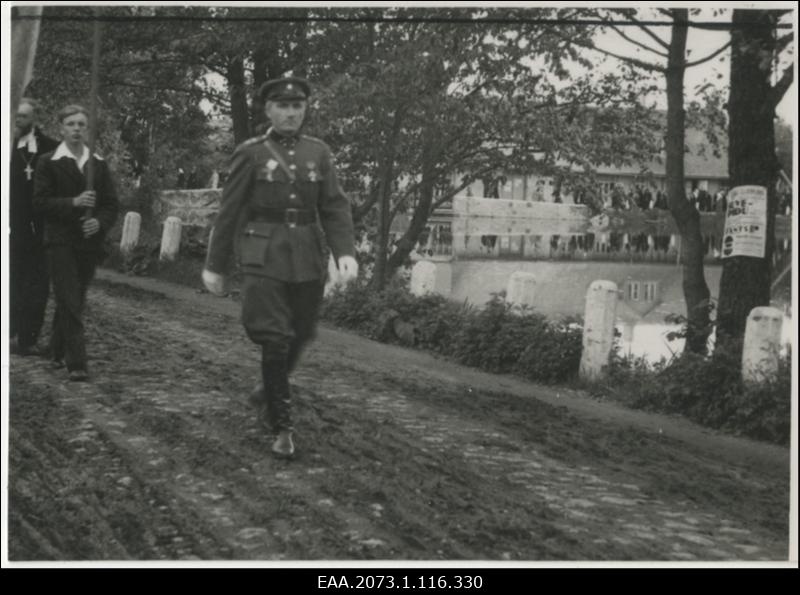 Lippudega rongkäik Palamusel, kaitseliitlane ees marssimas