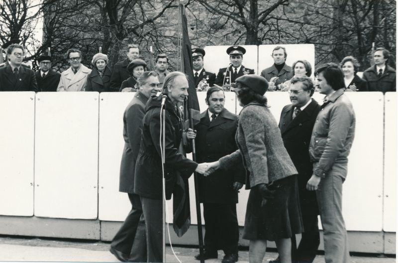 Foto. 1980.a. maimiitingul Elmu Peek ja Hans Mägedi üle andmas rajooni rändpunalippu  "Lääne Kalur" esindajatele.