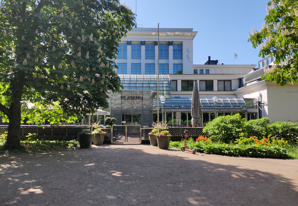 Ruotsalainen teatteri Teatteriesplanadin suunnasta kuvattuna. Koira päivystää ravintolan vasta auenneen terassin edustalla. rephoto
