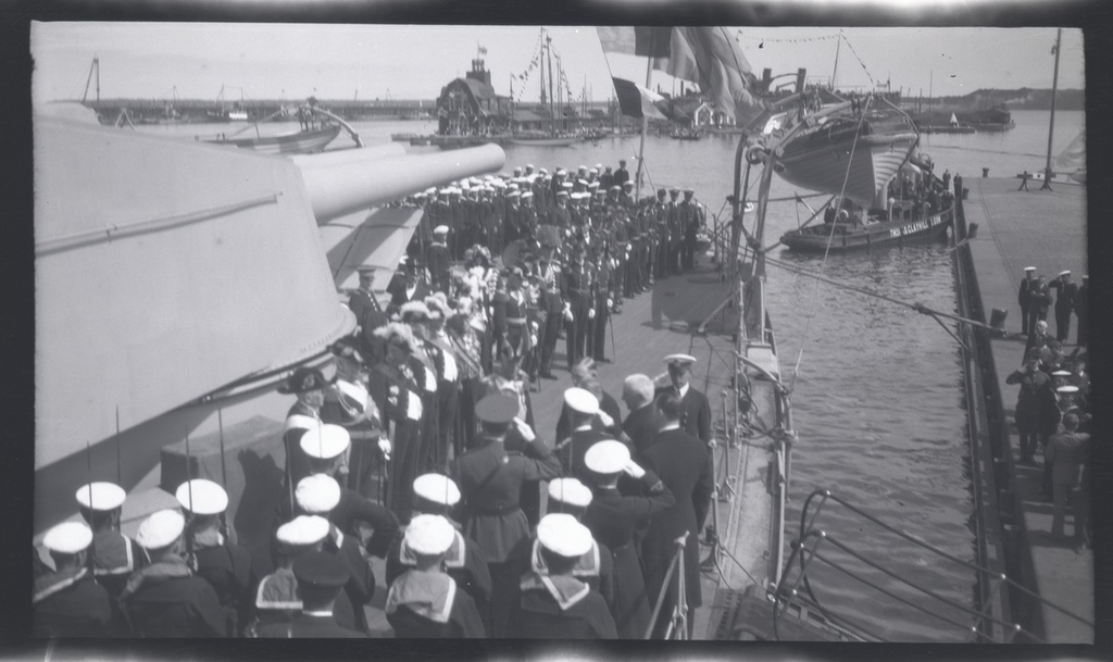 Från Gustaf V:s statsbesök i Tallinn 27-28 juni 1929; kungen anländer på pansarskeppet SVERIGE och hälsas på däck av estniska representanter. I bakgrunden bogserbåten TUTTI från estniska handelshuset Thomas Clayhill & Son.