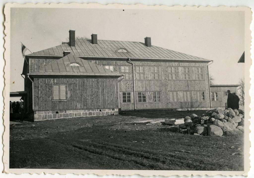 Kahekorruseline puidust koolimaja, vastvalminud. Vaade hoone külgfassaadile, õuel ehitusmaterjalid.