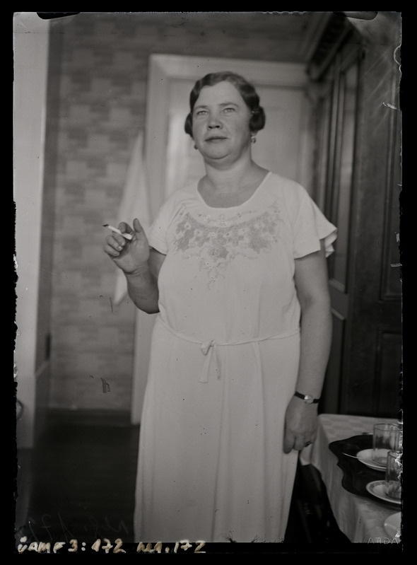 Tundmatu naise täisfiguurportree. Elutoas seismas ja suitsetamas.