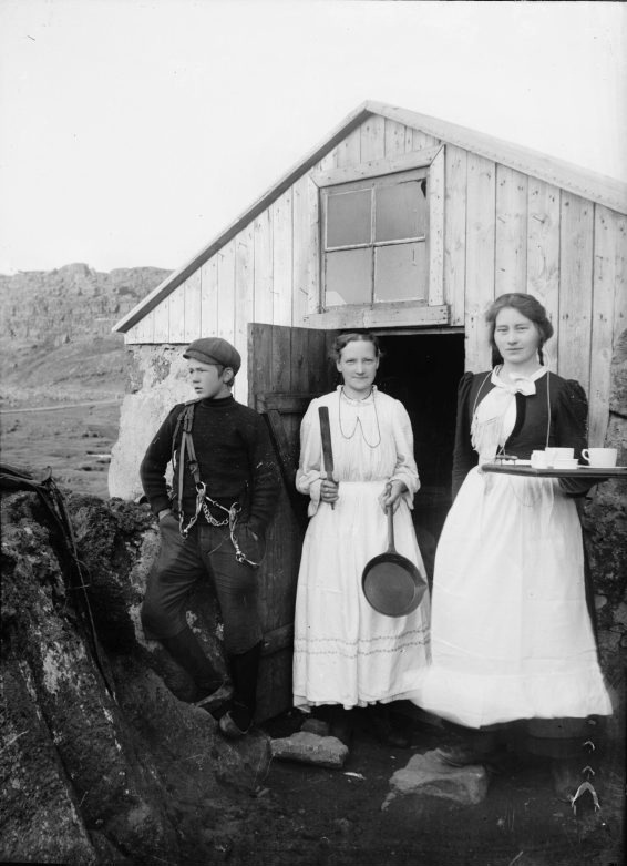 Tvær Konur og drengur fyrir framan timburbyggingu á Þingvöllum, 1907