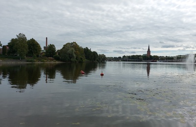 mies rannalla, taustalla vasemmalta Porin Puuvillan rakennuksia, silta ja Keski-Porin kirkko rephoto