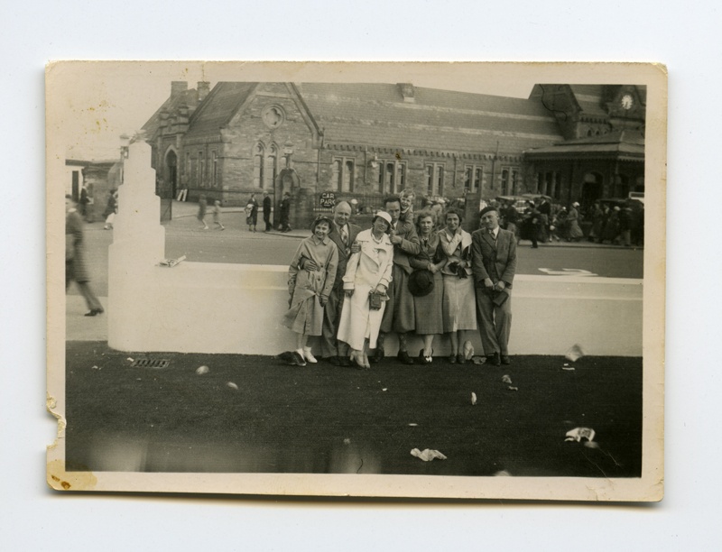 Seltskond väljasõidul; tagaplaanil vana hoone