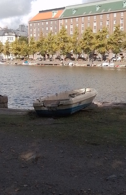 Kolme henkilöä nostaa venettä Kaisaniemenlahden rannalla rephoto