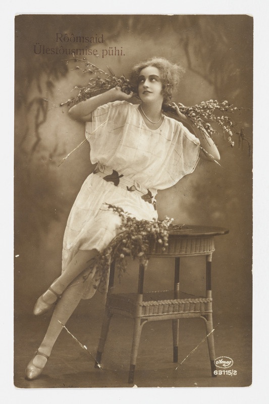 Romantiline lihavõttekaart lauale nõjatuva pajuokstega naisega ning tekstiga "Rõõmsaid Ülestõusmise pühi"