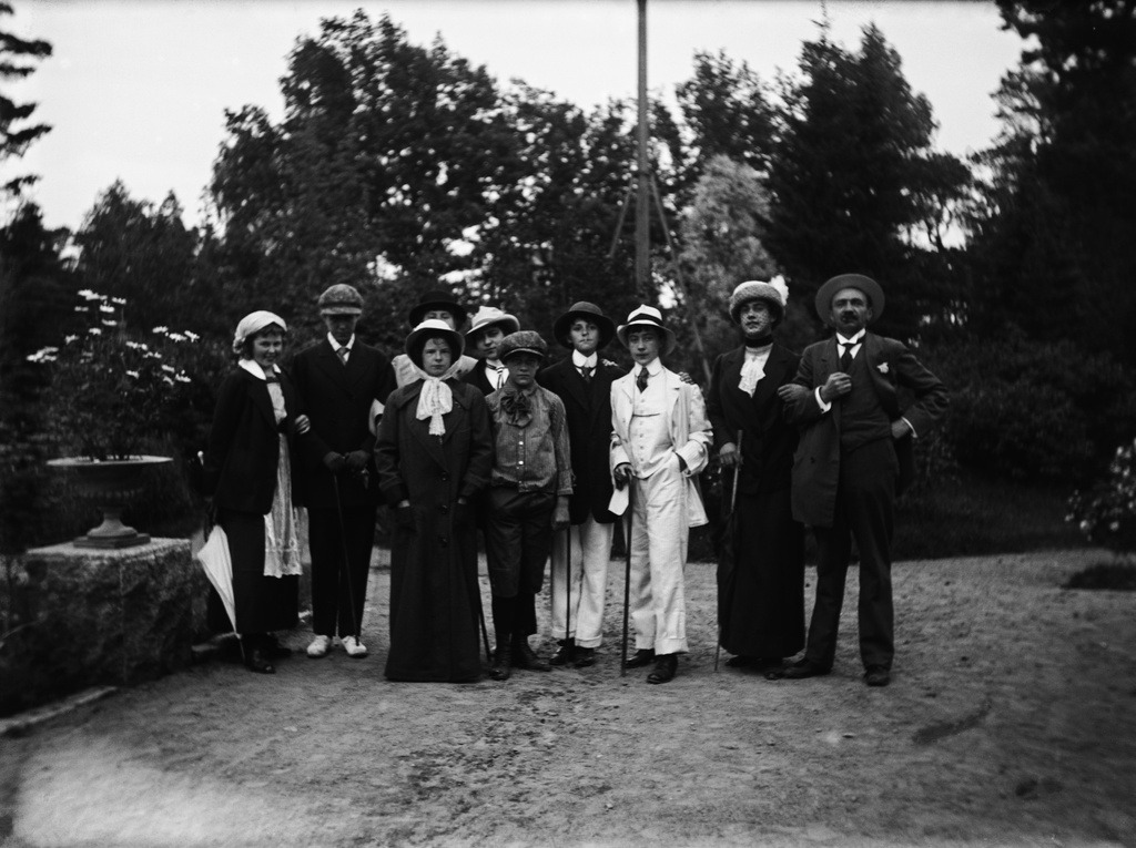 Villa Nissen (vuodesta 1914 lähtien nimi Villa Ekudden, nykyään Tamminiemi). Ryhmä pukeutuneina naamiaisjuhlia varten. Eturivissä keskellä lippalakki päässään Gurli Nyberg, hänen vieressään Lisbeth Nissen, jonka vieressä valkoisessa miesten puvussa Margit Nyberg. Margitin vieressä Ragnar Nyberg pukeutuneena naisten leninkiin ja hattuun. Äärimmäisenä oikealla on Villa Nissenin isäntä Jörgen Nissen.