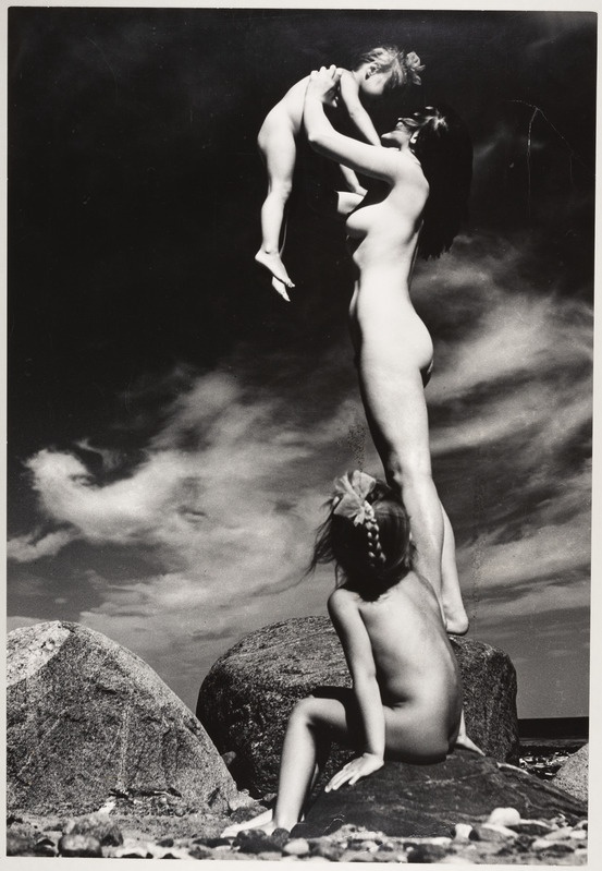 Rannas kivil seisev akt koos lastega.