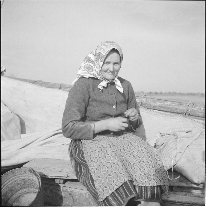 Vana naine Kihnu rahvariietes laevatekil istumas