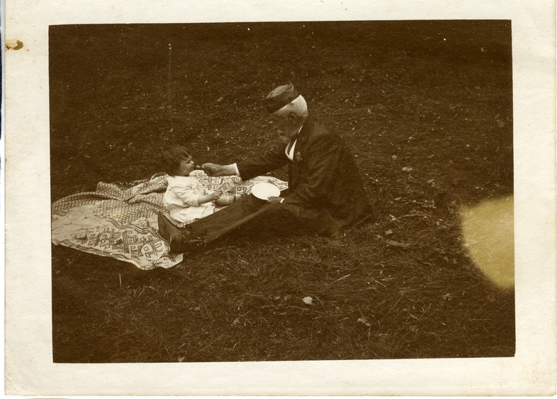 Vanem mees väikest last õues söötmas  (arvatav aeg XX saj. algus).
