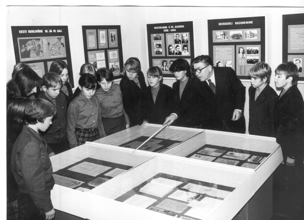 Foto. Vastseliina Keskkooli ajalooõpetaja Jüri Naarits õpilasekskursiooni  juhendamas kooli muuseumis 1983.a.