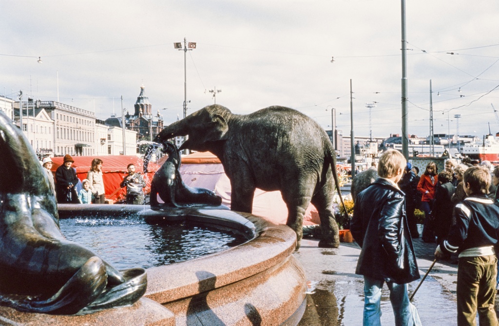 Sirkusnorsuja Havis Amandan suihkulähteellä, taustalla Uspenskin katedraali ja Viking linen laiva, joka aloitti liikennöinnin Helsingistä vuonna 1974