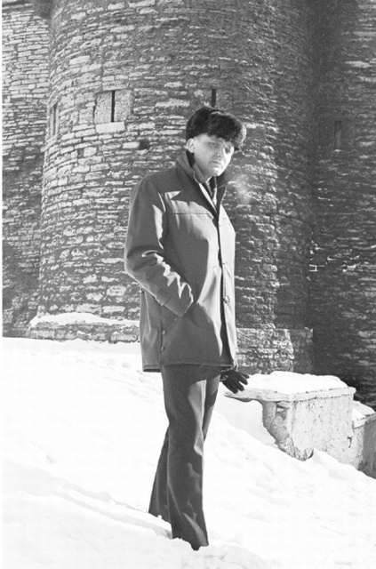 Luuletaja Arvi Siig seismas, käsi taskus Tallinna linnamüüri taustal.