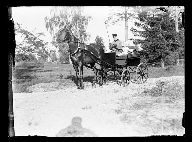 Vormirõivastuses mees ja väike laps hobuvankriga sõitmas