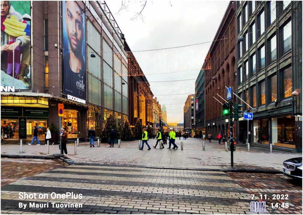 Näkymä Pohjoisesplanadilta Keskuskadulle, etualalla oikealla Keskuskatu 1a ja vasemmalla 2, Stockmannin tavaratalon urheiluosaston myymälä kaksikerroksisessa tiilirakennuksessa. rephoto