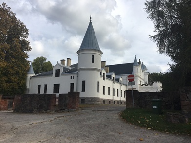 The main building of Alatskivi Manor is farther away. On the front of the grass, on the left road. Left and right trees. Lower borders from the brickstone, behind the centre of the manor building from the side. rephoto
