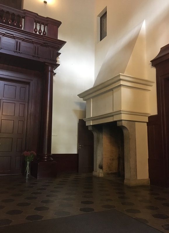 Alatskivi. The hall of the manor. On the left the dark door leads to indoors. On the right high white fireplace; on the white wall crocheted portraits of the manor owner's ancestors. rephoto