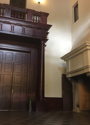 Alatskivi. The hall of the manor. On the left the dark door leads to indoors. On the right high white fireplace; on the white wall crocheted portraits of the manor owner's ancestors. rephoto