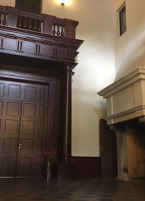Alatskivi. The hall of the manor. On the left the dark door leads to indoors. On the right high white fireplace; on the white wall crocheted portraits of the manor owner's ancestors. rephoto