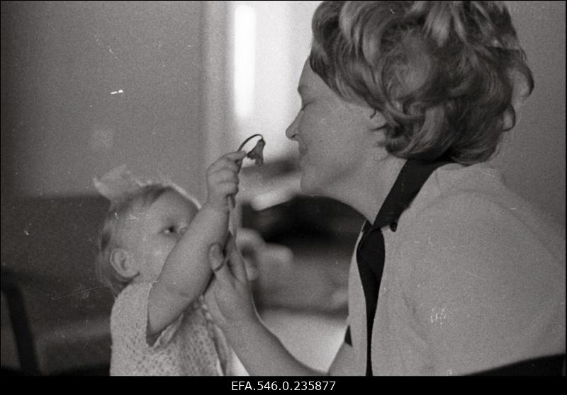 Väike tüdruk ulatab emale lille. (H.Leppikson "Lill emale")
