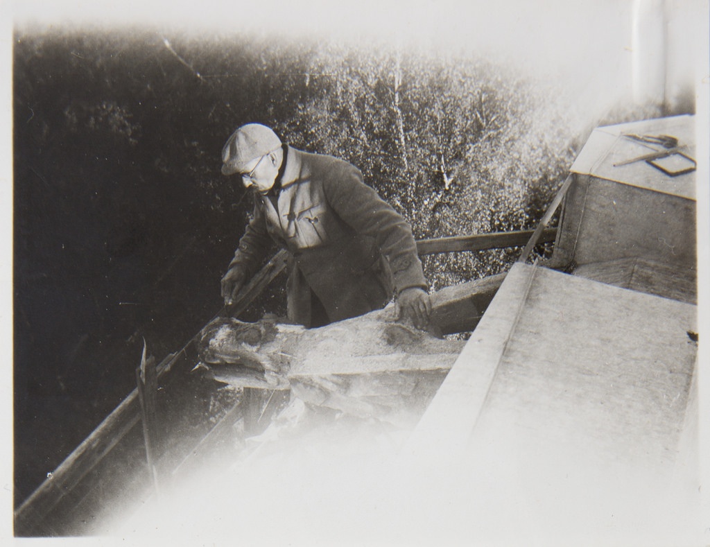Akseli Gallen-Kallela on the tower of Tarvaspää working on a dragon-shaped gargoyle, 1927; photograph 4.