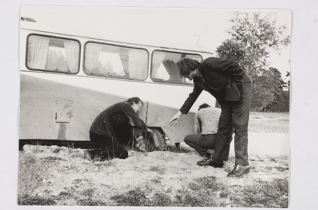 Kunstnik L. Lepp juhendab T. Linnust, kuidas autot liiva seest välja saada.