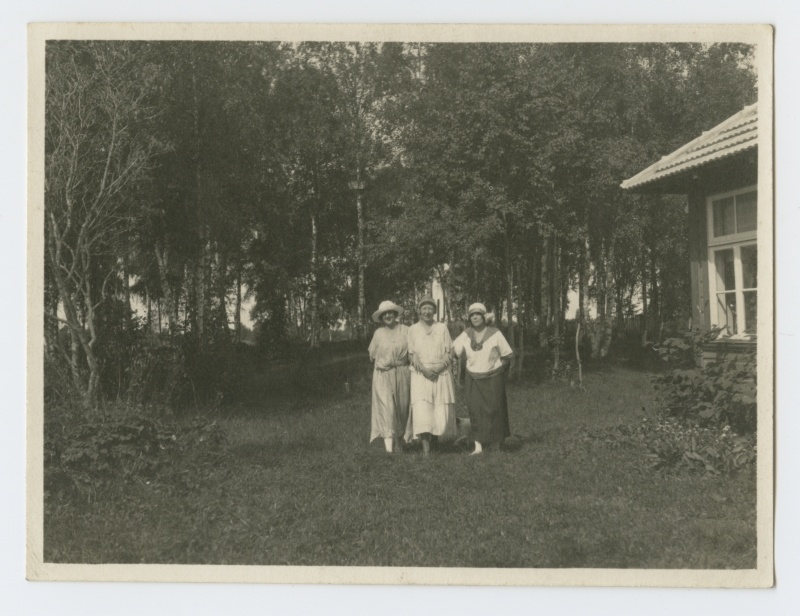 Grupifoto. Kolm naist maja kõrval aias
