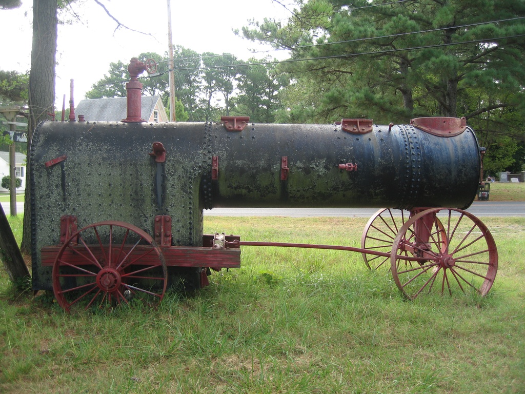 Frick Portable Engine 001 - Portable Steam Engine manufactured by Frick Company Engineers.  It is located at the "Y" intersection of Ridge Road and Bunting Road on Chincoteague Island, Virginia.  The address of the building next to this steam engine is 3625 Ridge Road.  The front end of the chassis has "Frick Company Engineers", "Patented Jan 10, 1882", "1243A", "Waynesboro, PA".