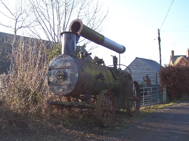 Portable Engine - geograph.org.uk - 113646 - (Not a...) Traction Engine. In need of a lot of Tender Loving Care. Close to the School House. This is not a traction engine: the wheels are far too lightweight for pulling anything. It is a 'portable engine' -- albeit missing all of its working parts -- which would have been towed to a farm or work site, not moved under its own power.