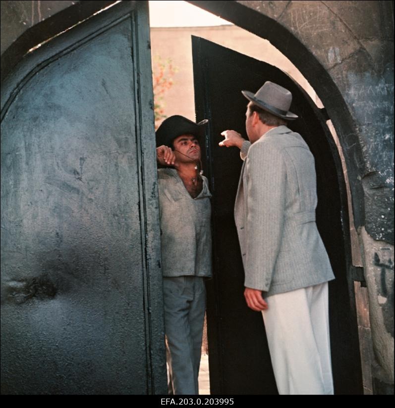 Stseen Tallinnfilmi mängufilmist "Bande". Ned Beamount (Tõnu Kark) püüab väravast sisse pääseda.