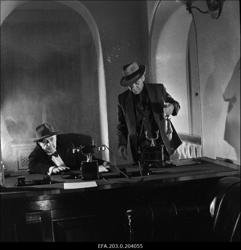 Stseen Tallinnfilmi mängufilmist "Bande". Istub Paul Madving (Aarne Üksküla), seisab Ned Beamount (Tõnu Kark).