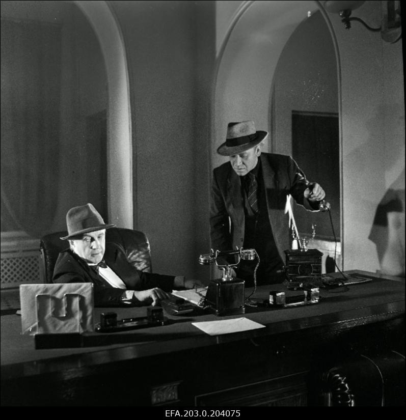 Stseen Tallinnfilmi mängufilmist "Bande". Istub Paul Madving (Aarne Üksküla), seisab Ned Beamount (Tõnu Kark).