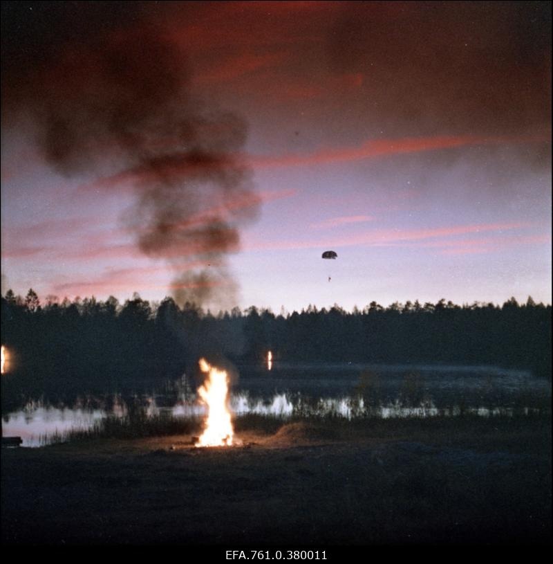 Stseen filmist "Metskannikesed". Märguandelõke järve kaldal, metsa kohal maanduv diversandist parašütist