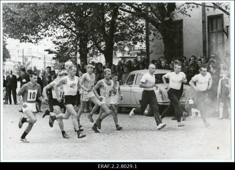 Rahvajooksul osalejad jooksevad Kuressaare tänaval. Eemal tänava äärel seisavad pealtvaatjaad