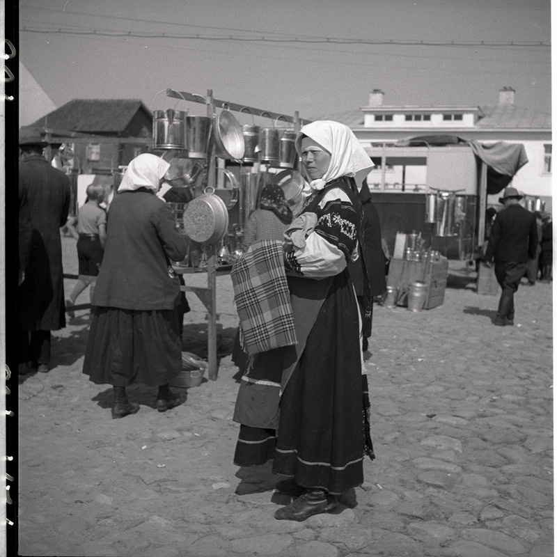 Setu rahvariietes naine Petseri laadal, taga köögitarvikud
