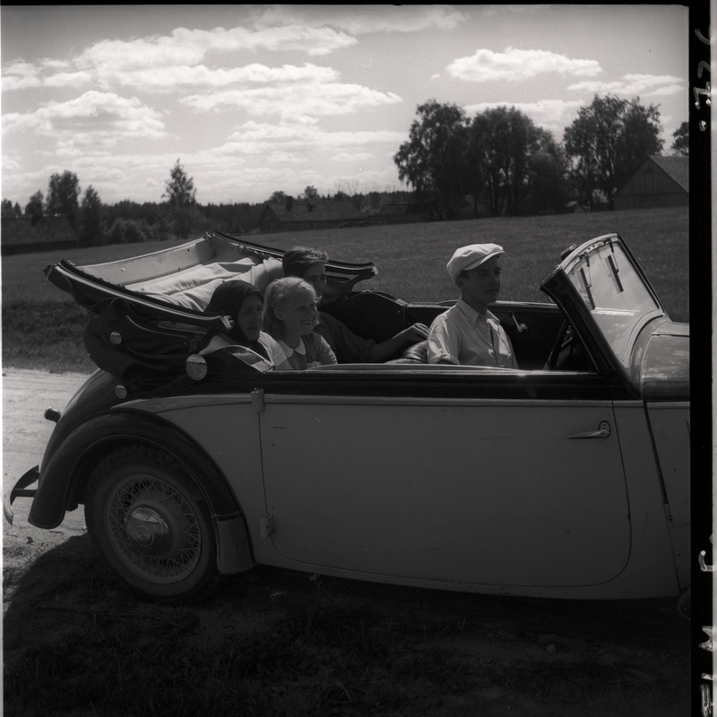 Sõiduauto külateel, auto tagapingil istuvad Johanna Triefeldt, Ingrid Millistfer ja Ülo Karl Sarap, ees istub autojuht Kruusberg.