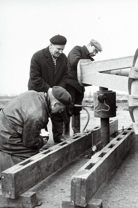 Eesti NSV Autotranspordi ja Maanteede Ministeeriumi teadusliku uurimise sektori juhataja A. Mechin (keskel) ja Moskva autoteede instituudi töötajad V. Parzdo ning J. Jakovlev määravad teekatte kandevõimet.