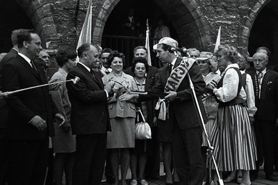 Harju rajooni TSN TK esimees Endel Jaama Tartust alates 1200km läbinud laulupeotuld Tallinna linna TSN TK esimehele Johannes Unduskile Raekoja ees üle andmas.  similar photo